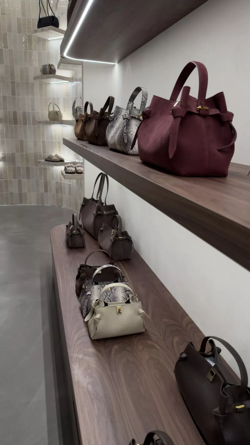 Handbags on lit walnut shelving in the Dublin boutique