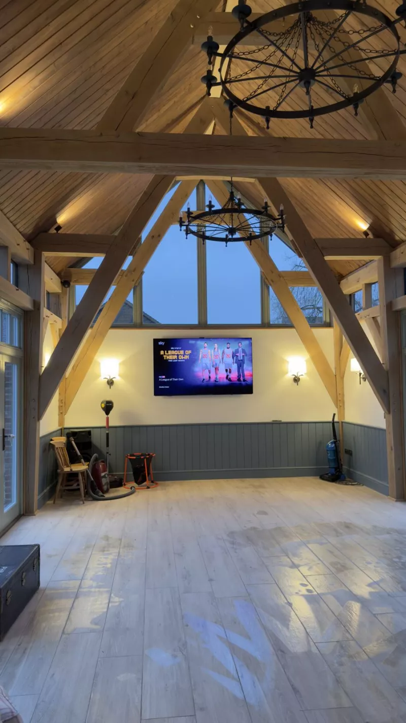 Oak framed room at night with the TV and lighting on