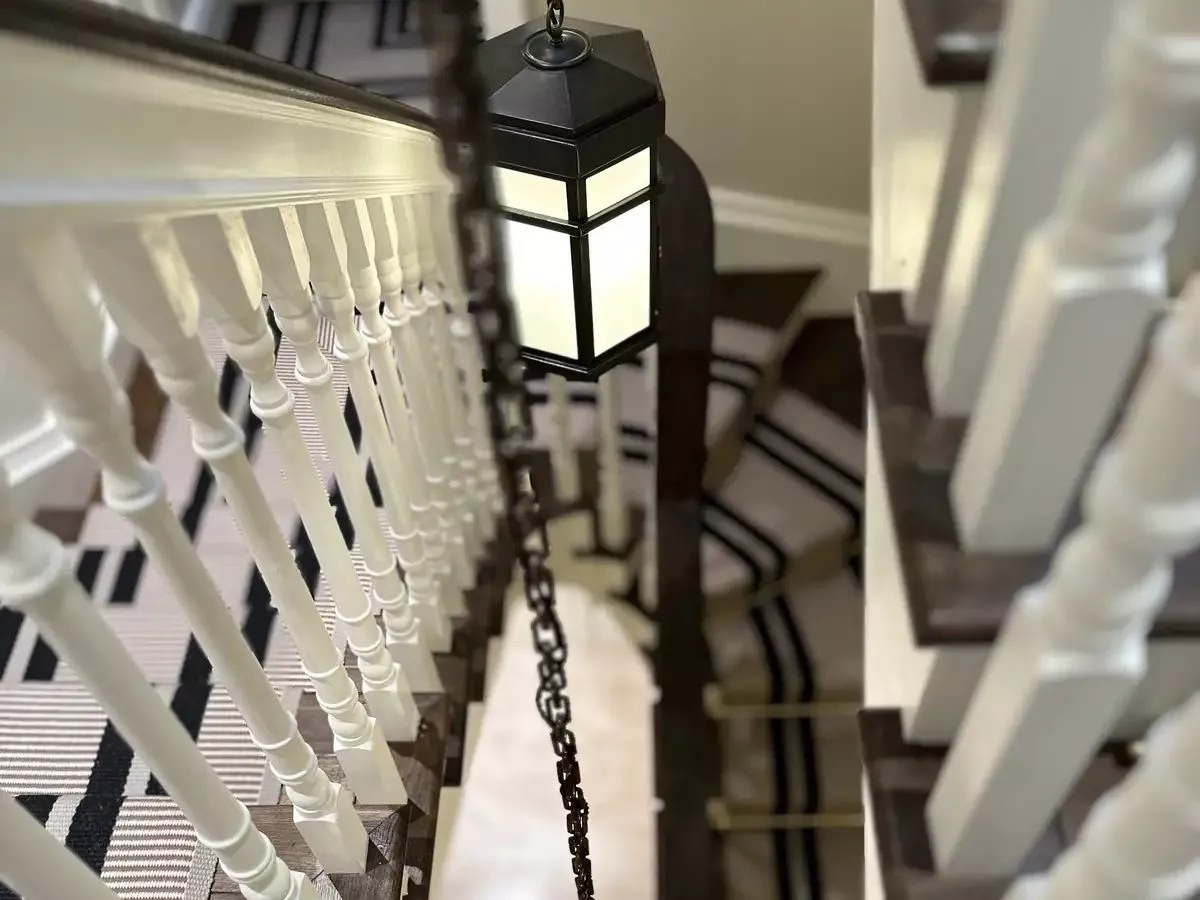 Lantern pendants beside white spindles on a stair, lighting a KNX installer in Limerick can dim from every floor