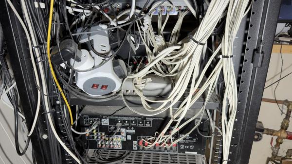 Control4 rescue in Cork: the back of an overloaded equipment rack, with power adaptors, a multi way power unit, an AV receiver and bundles of white cable