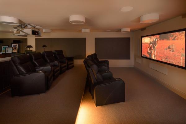 Two rows of black recliners facing a film on the projector screen