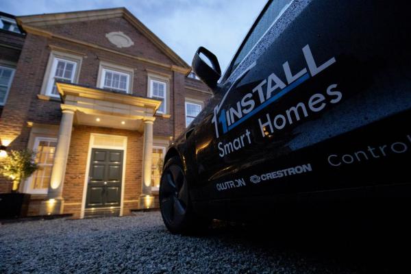 A 1Install car on the gravel in front of the house, with the porch and walls lit