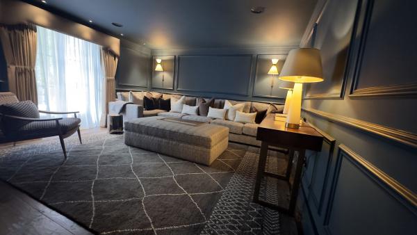 A panelled sitting room in dark blue, lit by wall lights and a table lamp