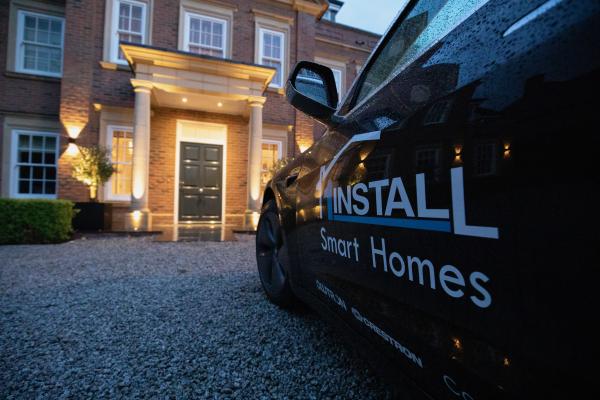 A 1Install vehicle parked in front of a house with its entrance lit at dusk