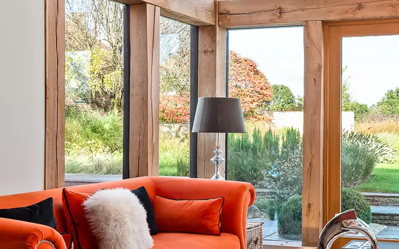 Warm living room with an orange sofa, a standing lamp and glazed doors to the garden