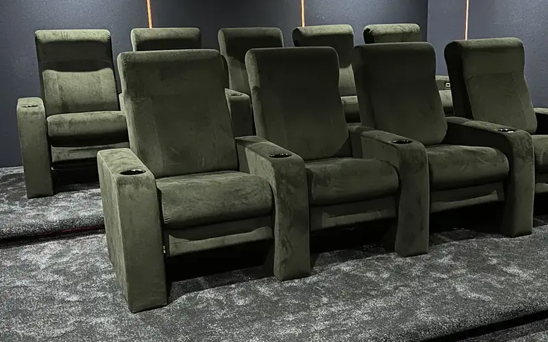 Home cinema with olive green velvet reclining seats on a grey carpet