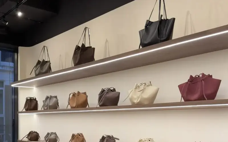 Boutique shelving with handbags and a continuous strip of light along each shelf