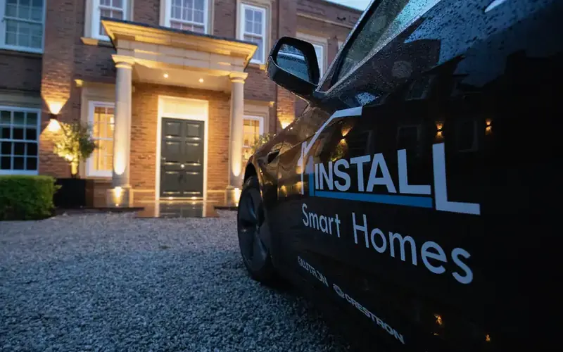 Dark 1Install branded vehicle parked outside the lit porch of a large brick house