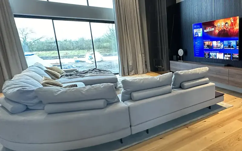 Cream corner sofa on a light oak floor, facing a TV set into dark timber slats