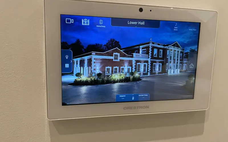 Wall mounted Crestron touch screen showing a house at night