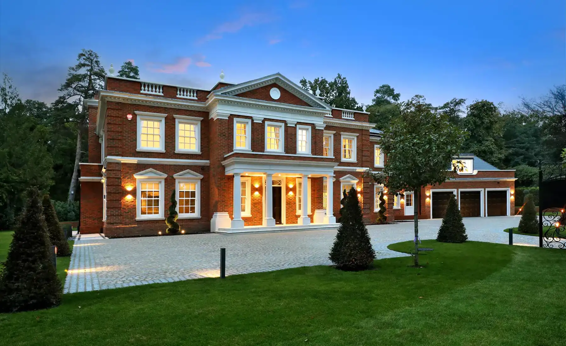 Large brick house lit up at dusk
